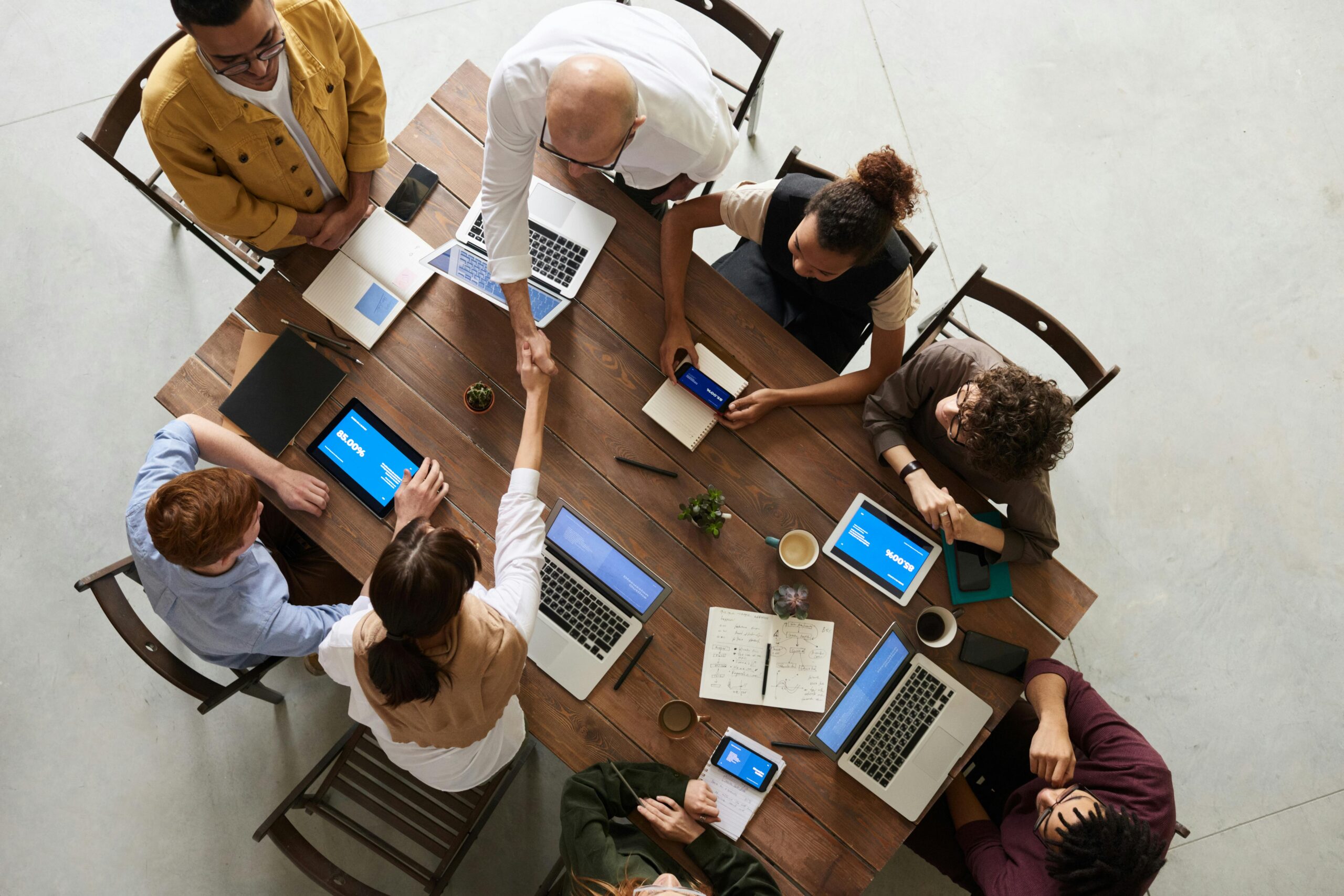 Diverse team collaborating around a table with laptops and tablets